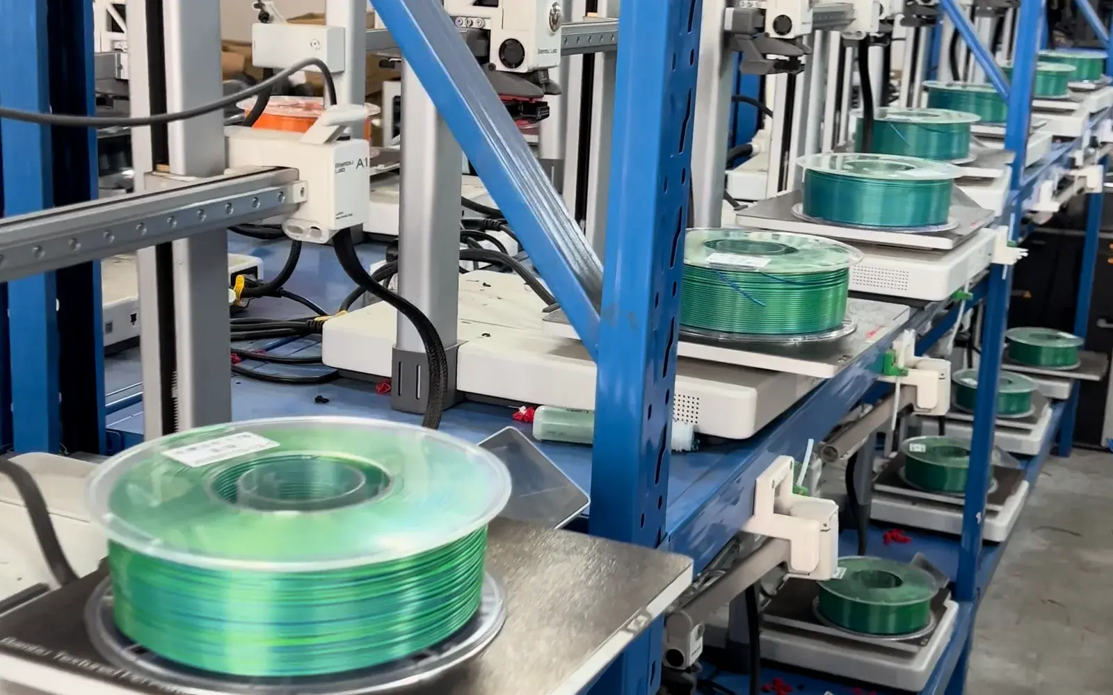 Green filament spools feeding a rack of FDM printers