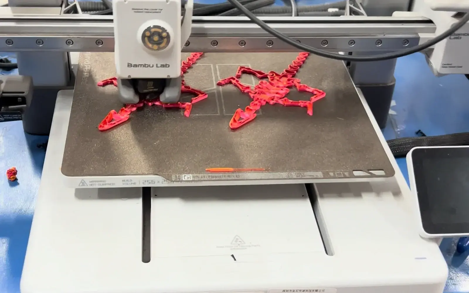 Red articulated model parts being printed on an open-frame machine