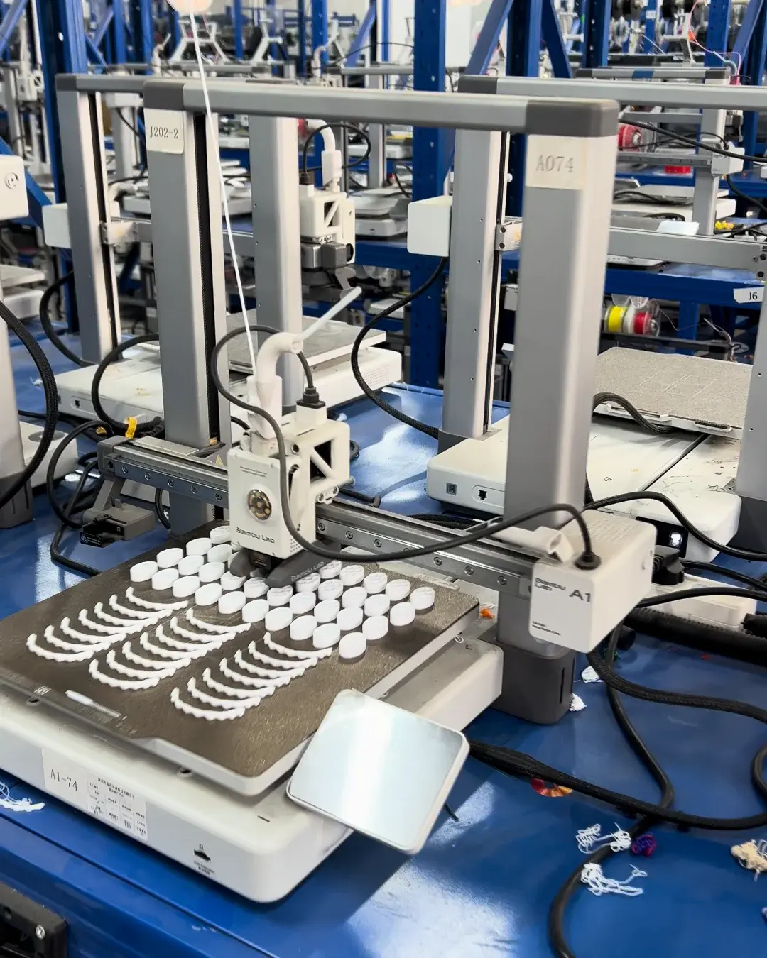 Multiple identical white parts being printed on an FDM build plate